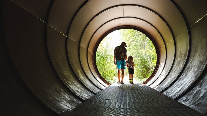 Ein Vater mit seinem Sohn in einer Stahlröhre im Natur Park Südgelände