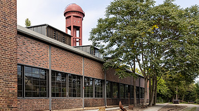 Außenansicht der Lokhalle im Natur Park Südgelände mit dem Wasserturm im Hintergrund